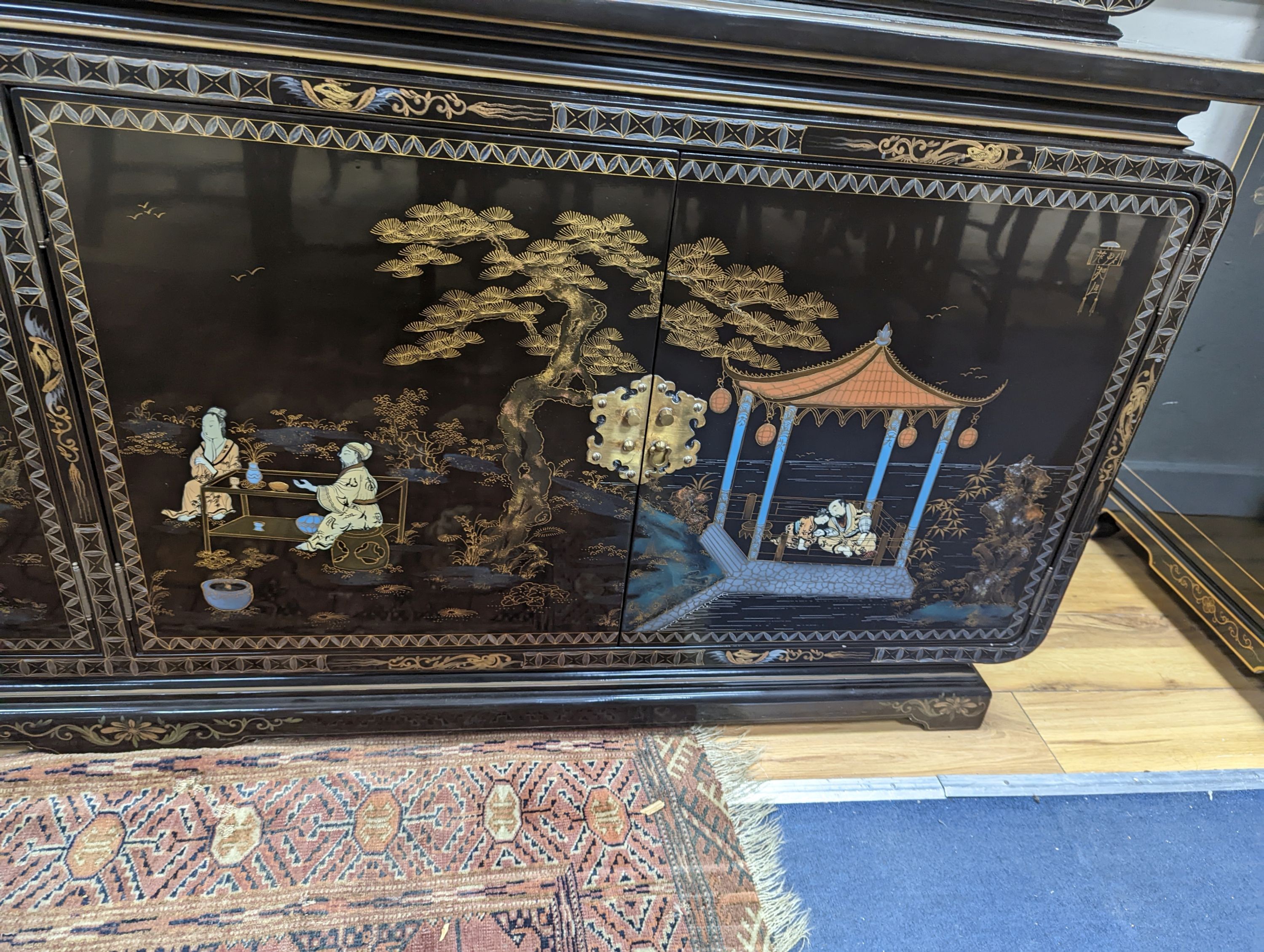 A Chinese lacquer decorated cabinet. W-200cm, D-45cm, H-201cm.